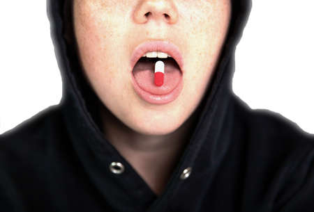 A woman is holding a pill, capsule with a drug on her tongue, teenager taking xtc.cocaine or other...