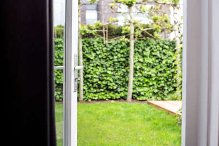 Close-up half opened modern door opening with blur green garden background in the summer of modern house new home with luxury styled outsideの写真素材