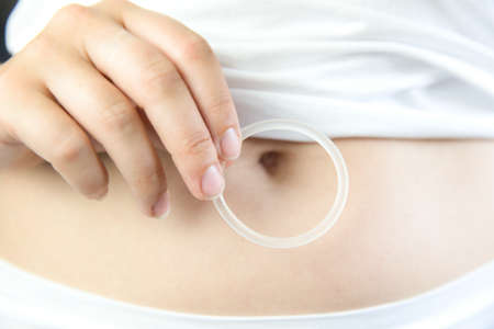 Birth control ,hormone, contraception ring in a womans hand white underwear and belly, vaginal ring for contraceptive use with copy spaceの写真素材