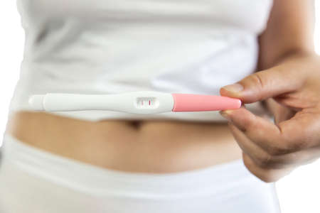 Young women wearing white underwear with hand holding positive result pregnancy test and belly. isolated on white backgroundの写真素材