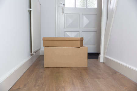 Stack of Cardboard boxes blank in the Hallway of new home on the floor. Moving, storage or delivery concept. Copy spaceの写真素材