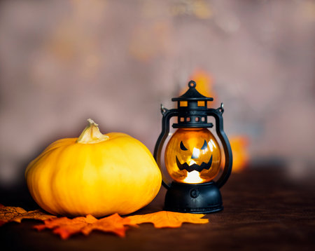 Halloween pumpkin on Autumn leaves and Jack o lantern on brown wooden background texture, Halloween,Fall and October conceptの写真素材