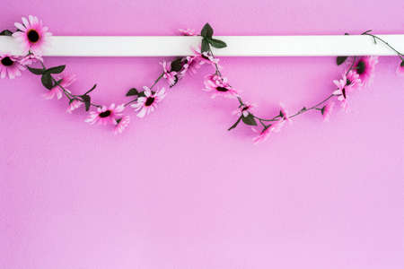 Cheerful, colorful pink, purple daisies garland hanging on pink wall background texture. beautiful modern design with copy spaceの写真素材