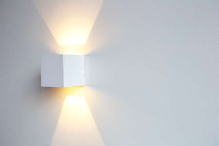 A glowing modern aluminum led lamp on white wall in retro home decoration with copy space. Luxury designの写真素材