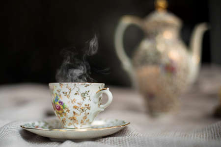 Porcelain tea pot and cup of hot tea on the table, antique traditional crockery set, high tea English afternoon teaの写真素材
