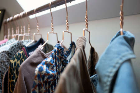 Hangers on rack with colorful stylish fashion clothes in modern room. House interior, fashion and...