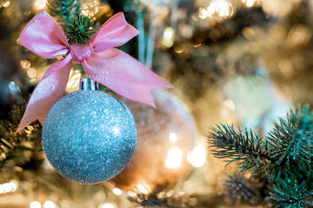 Sparkling Christmas bauble with pink bow hanging in decorated tree, copy space and bokeh light background, Holiday conceptの写真素材