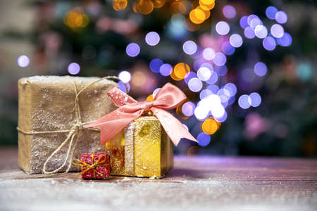Merry Christmas, New Year, gifts in gold boxes with pink bow in the snow, bokeh Christmas tree background with copy space, Holiday,present conceptの写真素材