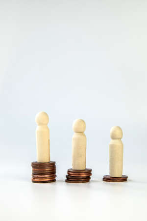 Miniature people standing on piles of different heights of coins. The concepts of person and wealth....