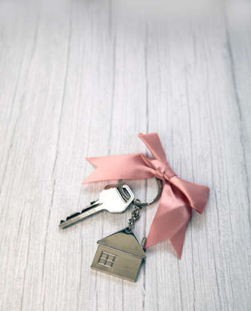 New keys of a house silver with keychain of little house top view with copy space and white wooden background, space for textの写真素材