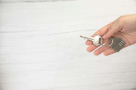 realtor female hand holding new door key to new house on white background top view with copy space, buying new home concept space for textの写真素材