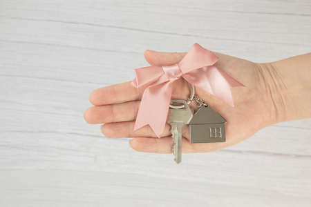 realtor female hand holding new door key to new house on white background top view with copy space, buying new home concept space for textの写真素材
