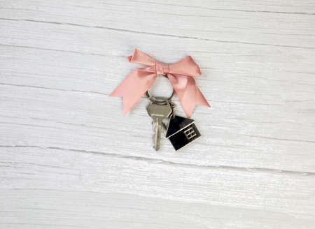 New keys of a house silver with keychain of little house top view with copy space and white wooden background, space for textの写真素材
