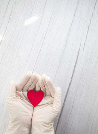 red heart in white protective medical gloves top view, background for the day of the medic, covid-19, coronavirus, hospital concept copy spaceの写真素材