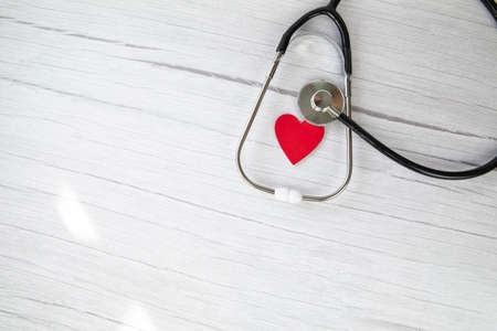 Red heart and a medical stethoscope, insurance,hospital,world health day concept top view on white wooden background copy spaceの写真素材