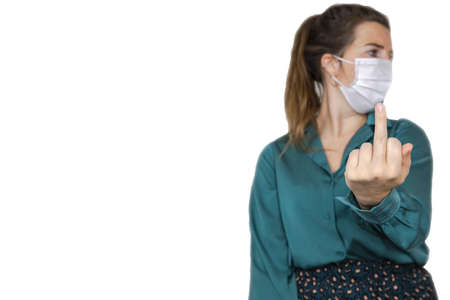 Female raise the middle finger middle finger hand sign wearing a white protective facial mask for...