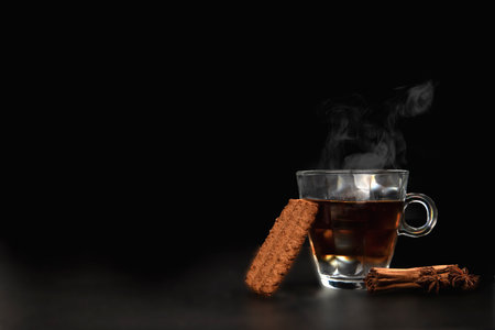 A glass of freshly brewed black tea, escaping steam, warm soft light, darker background. copy space healthyの写真素材