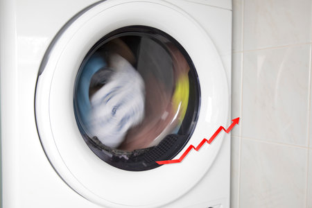 Concept of saving electricity with a washing machine white electrical power strip and red arrow up. Financial home savings conceptの写真素材