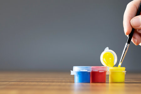 Artist paint brush with colorful paint on wooden table with gray background, copy space blue, red and yellow close upの写真素材