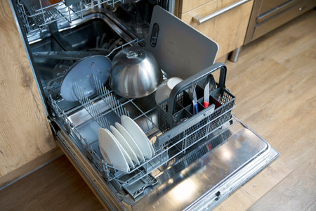 Stack of dirty dishes in dishwasher needs to be cleaned, open door with plates and dishes high angle view close upの写真素材