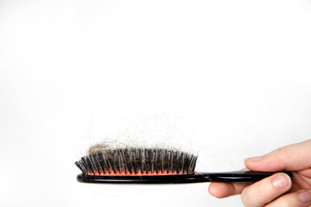 Hair loss problem, postpartum period, menstrual or endocrine disorder, hormonal imbalance, stress concept. Many hair fall after combing in hairbrush.Female untangles her hair with a comb, copy space close upの写真素材