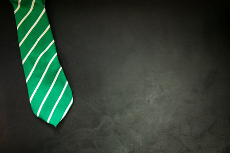 stylish tied green striped tie on dark concrete background top view, copy space, men,business,meeting,party concept maleの写真素材