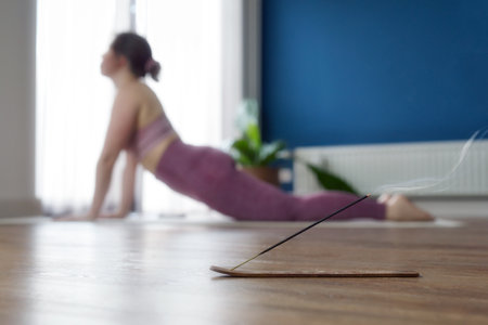 Young sporty woman practicing yoga at home, doing upward facing dog exercise, Urdhva mukha shvanasana pose, working out, wearing sportswear, pants and top, indoor full length, Yoga in living room sunlightの写真素材