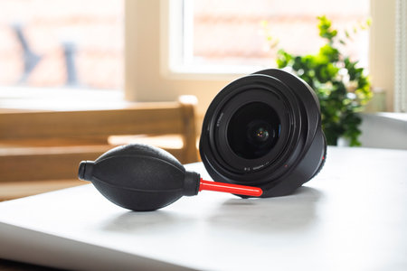 Lens on desk with cleaning tools for DSLR and Mirrorless cameras. Cleaning kit for cmos surface. Air blower, swab, isopropyl alcohol dropper and microfyber cloths. Lens and camera cleaning solution for professionals. close upの写真素材