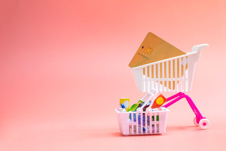 Shopping cart full with groceries and credit card, Shopping and e-commerce concept. Close up of four miniature shopping carts with copy space on pink background shopping conceptの写真素材