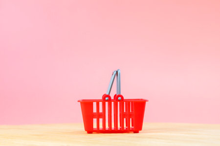 Empty red shopping basket on pink background supermarket background for grocery shopping on wooden...