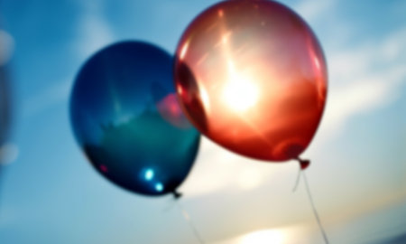 multicolored helium balloons in the blue sky, festival background blurred defocused. Happy Birthday party concept red and blueの素材
