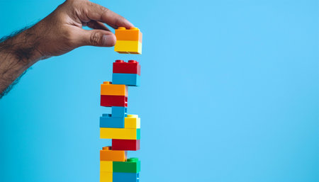 Man hand building with colorful Lego. Hand build blocks and going to add the final piece between the gap to complete, concept of help solution, solve the disconnect problem. Hobby toys Copy spaceの素材