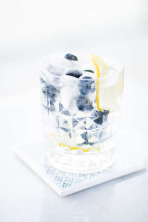 drinks, cocktails and celebration styled concept - cocktail with blueberry ice and lemon