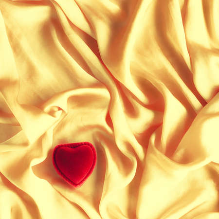 Red heart shaped jewellery gift box on golden silk - Valentine's day, true love, engagement and proposal concept. Will you marry me?の写真素材