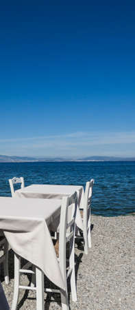 White restaurant tables on the beach in summer - travel, vacation and summer concept. The perfect lunch with a sea viewの写真素材