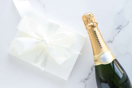 Wedding celebration, lifestyle and luxury present concept - A champagne bottle and a gift box on marbleの写真素材