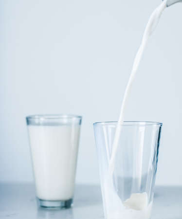 Dairy, healthy nutrition and breakfast concept - World Milk Day, pouring into glass on marble table