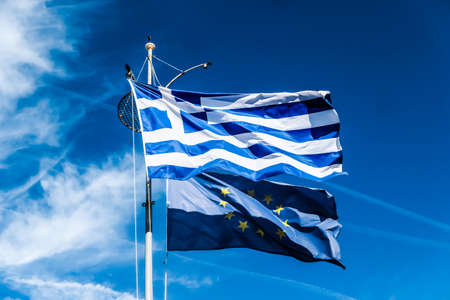 European political news, grexit and nation concept - Flags of Greece and European Union on blue sky background, politics of Europeの写真素材