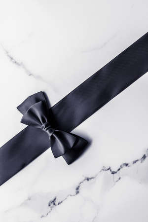 Holiday gift, decoration and sale promotion concept - Black silk ribbon and bow on marble background, flatlayの写真素材