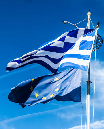 European political news, grexit and nation concept - Flags of Greece and European Union on blue sky background, politics of Europeの写真素材