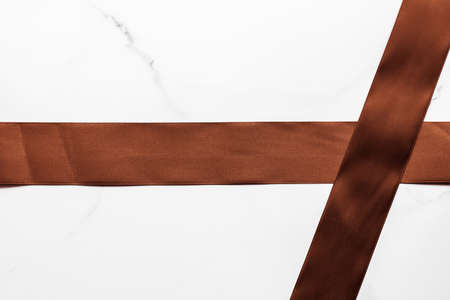 Holiday gift, decoration and sale promotion concept - Chocolate brown silk ribbon on marble background, flatlayの写真素材