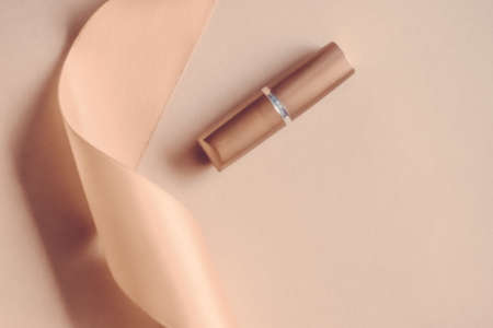Cosmetic branding, glamour lip gloss and shopping sale concept - Luxury lipstick and silk ribbon on beige holiday background, make-up and cosmetics flatlay for beauty brand product designの写真素材