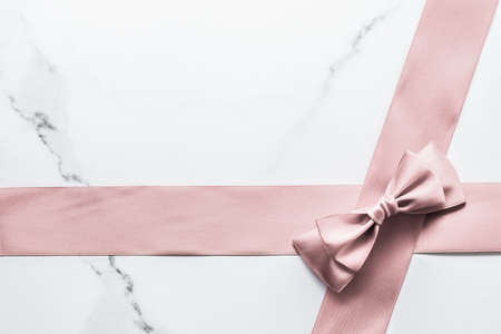 Birthday, wedding and girly branding concept - Beige silk ribbon and bow on marble background, glamour present mockup and fashion gift decoration for luxury beauty brand holiday flatlay designの写真素材