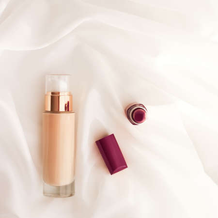 Cosmetic branding, glamour and skincare concept - Beige tonal cream bottle make-up fluid foundation base and dark lipstick on silk background, cosmetics products as luxury beauty brand holiday designの写真素材