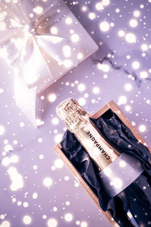 Celebration, drink and branding concept - Champagne bottle and gift box on purple holiday glitter, New Years, Christmas, Valentines Day, winter present and luxury product packaging for beverage brandの写真素材
