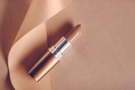 Cosmetic branding, glamour lip gloss and shopping sale concept - Luxury lipstick and silk ribbon on beige holiday background, make-up and cosmetics flatlay for beauty brand product designの写真素材