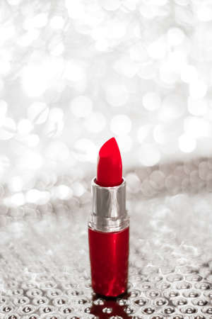 Cosmetic branding, sale and glamour concept - Red lipstick on silver Christmas, New Years and Valentines Day holiday glitter background, make-up and cosmetics product for luxury beauty brandの写真素材