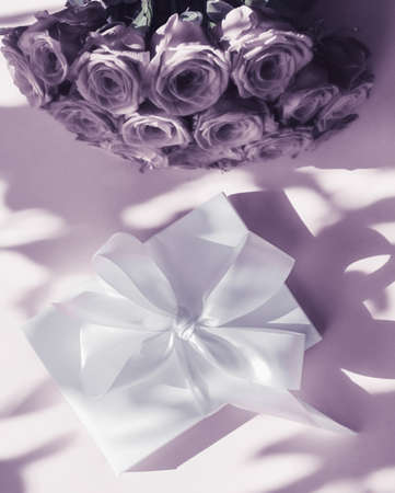 Happy holidays, luxe shopping and love gifts concept - Luxury holiday silk gift box and bouquet of roses on purple background, romantic surprise and flowers as birthday or Valentines Day presentの写真素材