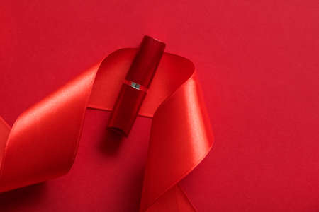 Cosmetic branding, glamour lip gloss and shopping sale concept - Luxury lipstick and silk ribbon on red holiday background, make-up and cosmetics flatlay for beauty brand product designの写真素材