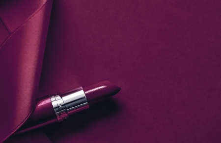 Cosmetic branding, glamour lip gloss and shopping sale concept - Luxury lipstick and silk ribbon on plum holiday background, make-up and cosmetics flatlay for beauty brand product designの写真素材